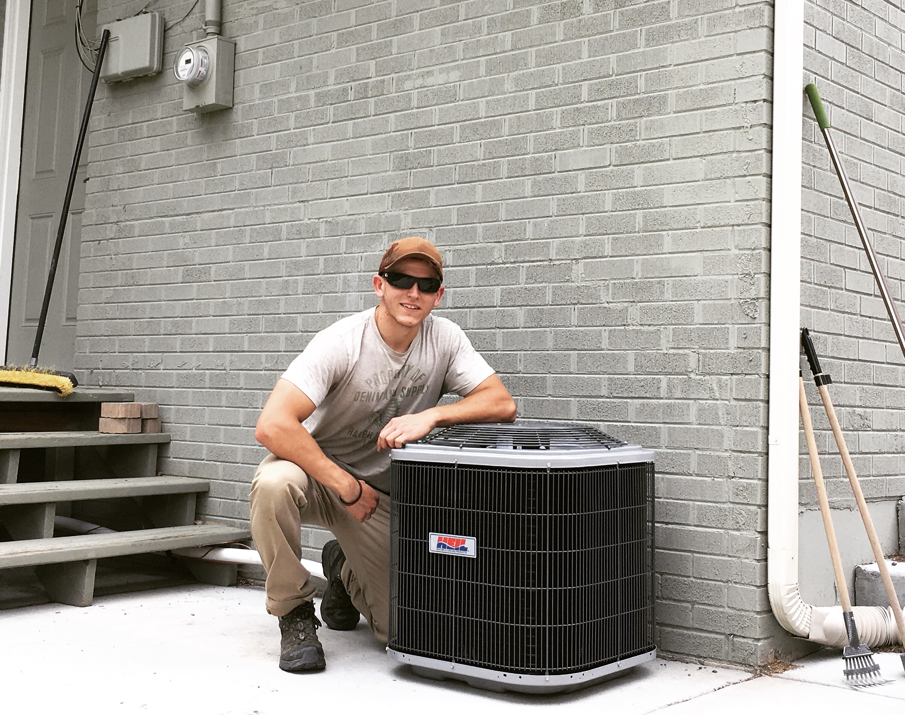 George Heiman kneels next to a freshly installed HVAC unit